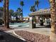 A community pool area features a covered pavilion, lounge chairs, and lush palm trees under a bright, clear sky at 213 Luninborg St, Henderson, NV 89074
