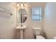 Small bathroom with a pedestal sink, a toilet, and a decorative light fixture at 2509 April Breeze Ln, Henderson, NV 89002