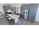 Modern kitchen features gray cabinets, stainless appliances, an island with seating, and luxury vinyl plank flooring at 2530 Commercial Dr, Pahrump, NV 89048