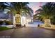 Elegant home featuring lighted palm trees, a driveway, and stucco exterior at 2608 Sun Reef Rd, Las Vegas, NV 89128