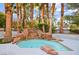 Tranquil backyard pool with an eye-catching rock waterfall feature and mature palm trees at 2608 Sun Reef Rd, Las Vegas, NV 89128