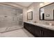 Bathroom featuring dual sinks, granite countertops, frameless glass shower with tile surround and rainfall showerhead at 29 Costa Tropical Dr, Henderson, NV 89011