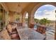 Covered patio with outdoor dining area, stone columns, and views of the pool and desert landscape beyond at 29 Costa Tropical Dr, Henderson, NV 89011