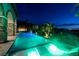 Luxury pool featuring underwater lighting and lounge chairs, set against a backdrop of palm trees and city lights at 29 Costa Tropical Dr, Henderson, NV 89011