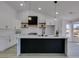 Bright, modern kitchen boasts white cabinetry, a black island, and stainless steel appliances at 2905 Legend Dr, Las Vegas, NV 89134