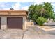 Attached single-car garage with a brown door, alongside a landscaped area with a mature tree at 5101 Renault Ave, Las Vegas, NV 89142