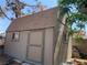 A neutral-colored exterior shed with a brown roof is nestled among trees in the backyard at 6704 Lost River Ct, Las Vegas, NV 89108
