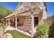 The covered patio features a pergola, artificial turf and landscaped yard at 7263 Pepperbox Ave, Las Vegas, NV 89179