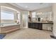 Bright main bathroom features a soaking tub, tile flooring, double sinks, and a large mirror at 7854 Brianna Cheerful Ave, Las Vegas, NV 89178