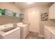 Laundry room with white washer and dryer, storage shelves and utility sink at 8221 Ebony Peak St, Las Vegas, NV 89143