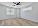 Bright bedroom with modern ceiling fan, two windows, and light wood-look flooring at 8944 W Rochelle Ave, Las Vegas, NV 89147