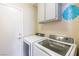 Laundry room with washer, dryer, overhead cabinets, and access door at 902 Possum Hill St, Henderson, NV 89014