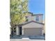 Beige two-story home with an attached two-car garage and a well-maintained front yard at 908 Shining Rose Pl, Henderson, NV 89052