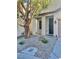 Landscaped front yard with decorative rock features, plants, and a mature shade tree at 908 Shining Rose Pl, Henderson, NV 89052