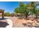Private backyard with mature landscaping, a stone patio, and desert landscaping, with the home in the background at 9800 Rosamond Dr, Las Vegas, NV 89134