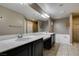 Bathroom with double sinks, a soaking tub, a glass-enclosed shower, and neutral tiling at 11063 Mount George St, Las Vegas, NV 89179