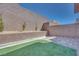 Secluded backyard featuring artificial turf, a brick patio, and a high privacy wall with young trees at 11922 Glide Reflection Ave, Las Vegas, NV 89138