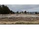 Large lot with mature trees, a white fence, a home, and views of the local mountains at 2451 E Falcon St, Pahrump, NV 89048