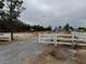 Large lot with mature trees, a white fence, a gate, and a home with mountain views at 2451 E Falcon St, Pahrump, NV 89048
