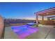 Backyard view of pool and hot tub with colored lights and covered patio with views to the desert landscape at 2787 Donatello Manor Pl, Henderson, NV 89044
