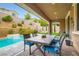 Covered patio with dining set views the backyard with a sparkling pool, water feature, and lush landscaping at 391 Capistrano Vistas St, Las Vegas, NV 89138