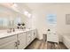 Bright bathroom features a double sink vanity with white cabinets and wood look flooring at 391 Capistrano Vistas St, Las Vegas, NV 89138