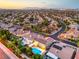 Expansive aerial shot of a community, highlighting mature trees, swimming pools, and well-manicured landscapes at twilight at 4045 Abernethy Forest Pl, Las Vegas, NV 89141
