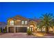Elegant two-story home featuring a three-car garage, arched entry, stone accents, and lush palm tree in landscaped yard at 4045 Abernethy Forest Pl, Las Vegas, NV 89141