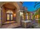 Elegant front entrance with stone accents, arched doorway, decorative glass doors, and manicured landscaping at 4045 Abernethy Forest Pl, Las Vegas, NV 89141