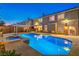 Backyard pool and spa illuminated at twilight, with covered patio and exterior of home in view at 4045 Abernethy Forest Pl, Las Vegas, NV 89141