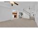 Open-concept living room with neutral carpet, stairs, and view into kitchen with breakfast bar at 5653 Mount Athos St, North Las Vegas, NV 89031