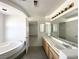 Bright bathroom with double sink vanity, tile flooring, soaking tub, and doorway to bedroom at 6571 Abalone Shell Ct, Las Vegas, NV 89139