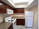 Compact kitchen with granite counters, white appliances, and wooden cabinets at 6800 E Lake Mead Blvd # 2024, Las Vegas, NV 89156