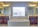 Bright bathroom featuring a soaking tub, dual vanities, and a large window at 72 Broken Putter Way, Las Vegas, NV 89148