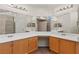 Bathroom featuring dual sinks, wood cabinets, a makeup vanity, and a tiled walk-in shower at 7825 White Grass Ave, Las Vegas, NV 89131