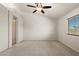 Spacious bedroom with neutral carpet, a ceiling fan, and a window with outside views at 7825 White Grass Ave, Las Vegas, NV 89131