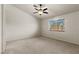 Bright bedroom featuring neutral carpet, a ceiling fan, and a window with outside views at 7825 White Grass Ave, Las Vegas, NV 89131