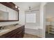 Bright bathroom with dual sinks, dark wood cabinetry, a soaking tub, and a window for natural light at 7849 Meandering Light Ave, Las Vegas, NV 89131