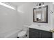 Well-lit bathroom featuring a tiled shower-tub, dark vanity with sink, and a decorative framed mirror at 7849 Meandering Light Ave, Las Vegas, NV 89131