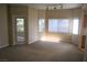 Bright living room featuring three windows with blinds, plush carpet, and a glass door leading to outdoor space at 830 Carnegie St # 1011, Henderson, NV 89052