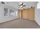 Spacious living room featuring neutral carpet, three windows, and a modern ceiling fan at 8562 Burning Bridge Ct, Las Vegas, NV 89131