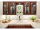 Elegant bar area featuring custom cabinetry with glass doors, marble countertop, and decorative backsplash at 9135 Hickam Ave, Las Vegas, NV 89129