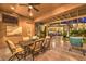 Relaxing covered patio with ceiling fan, outdoor dining, tv, and additional seating area at dusk at 9135 Hickam Ave, Las Vegas, NV 89129