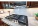Close-up of a stainless steel stove top with marble countertop and backsplash in a modern kitchen at 9135 Hickam Ave, Las Vegas, NV 89129
