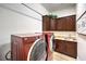 Functional laundry room featuring front-load machines, wooden cabinets, a utility sink, and an overhead hanging bar at 9135 Hickam Ave, Las Vegas, NV 89129
