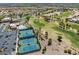 Aerial view features golf course, tennis courts, a community pool and clubhouse, and residential houses under sunny skies at 10413 Marymont Pl, Las Vegas, NV 89134