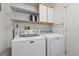 Bright laundry room with a white washer and dryer, shelves, and cabinet at 10413 Marymont Pl, Las Vegas, NV 89134