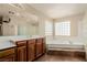 Bright bathroom with large mirror, tile flooring, glass block shower and soaking tub at 1054 Broomfield Dr, Henderson, NV 89074