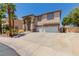 Two-story home featuring stucco siding, desert landscaping, an arched entryway, and a three-car garage at 1054 Broomfield Dr, Henderson, NV 89074
