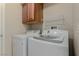 Well-lit laundry room with modern white washer and dryer and overhead cabinet at 1054 Broomfield Dr, Henderson, NV 89074